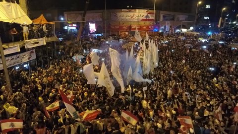 Tripoli Lebanon-October 2019: Close-up of revolutionists at night waving Lebanese army flag 