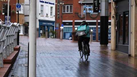 READING, UK - FEBRUARY 15, 2021: Deliveroo food delivery rider on a bicycle in Reading, Berkshire, UK.