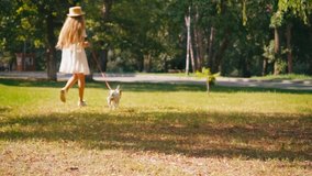 slow motion of girl in dress walking with jack russell terrier outside