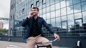 happy man talking on smartphone and sitting on bicycle