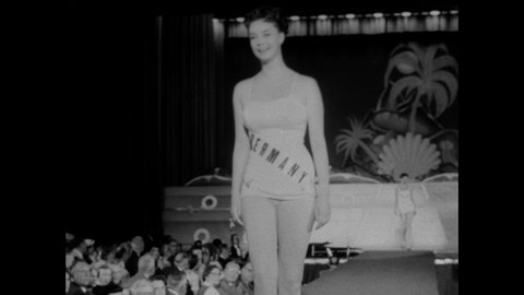 1950s: Women present themselves on stage in Miss Universe pageant. Winner walks across stage and accepts scepter and crown.