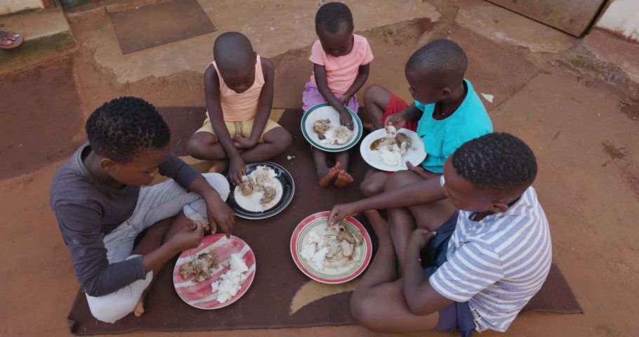 Poverty. Inequality. Poor young rural Black African children from an informal settlement slum are fed by a non-profit organisation in a feeding scheme at a squatter camp Royalty-Free Stock Footage #1067513354