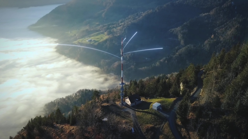 Antenna station on mountain above clouds in the valley sends out digital network lines with 5G data. Panoramic Drone Shot of Mountain Range in Sunlight. Telecom TV antennas Cellular distribution. Royalty-Free Stock Footage #1067521076
