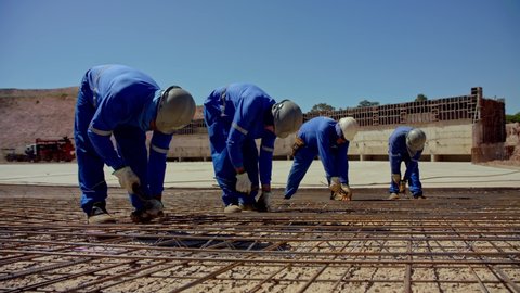 Brasilia , Brazil - 12 02 2020: Brasilia, Brazil - December 2020: line of men tying a grid or rebar before pouring the foundation