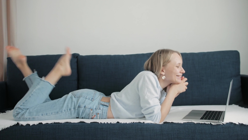 young girl communicates using a video call on a laptop lying on the couch