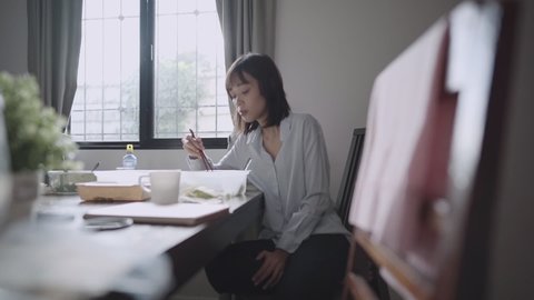 Asian working woman eating  at home, delivery food service, using chopsticks and spoon, food Delivery service take away Food, single woman stay alone, budget living, keep away distance, window light 