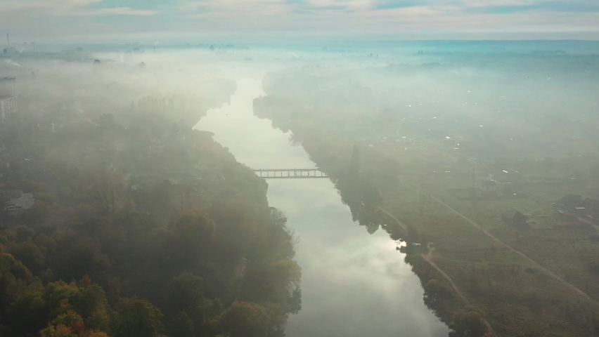 Beautiful morning, summer flight over the river. The bridge over the river in the fog, at dawn.