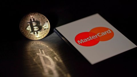 Bitcoin cryptocurrency coin with twisting motion, with phone, Mastercard payment system. Portugal Faro - 27 January 2021