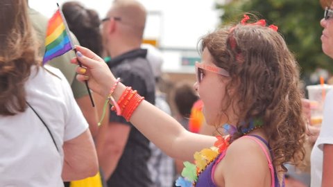 Colorado June 2015. 
Excited happy little girl waves rainbow flag at Gay Pride parade in slow motion. Circa Denver, Colorado June 2015. 