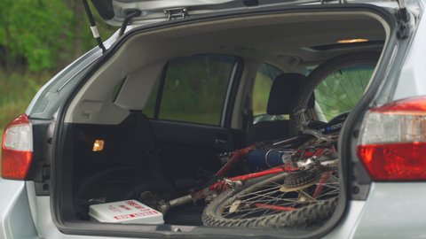 Altoona , PA , United States - 07 24 2020: ALTOONA, PA - JUL. 24, 2020: Young man packs a Subaru Crosstrek with mountain bike and hiking backpack for a camping trip in the summer in Pennsylvania