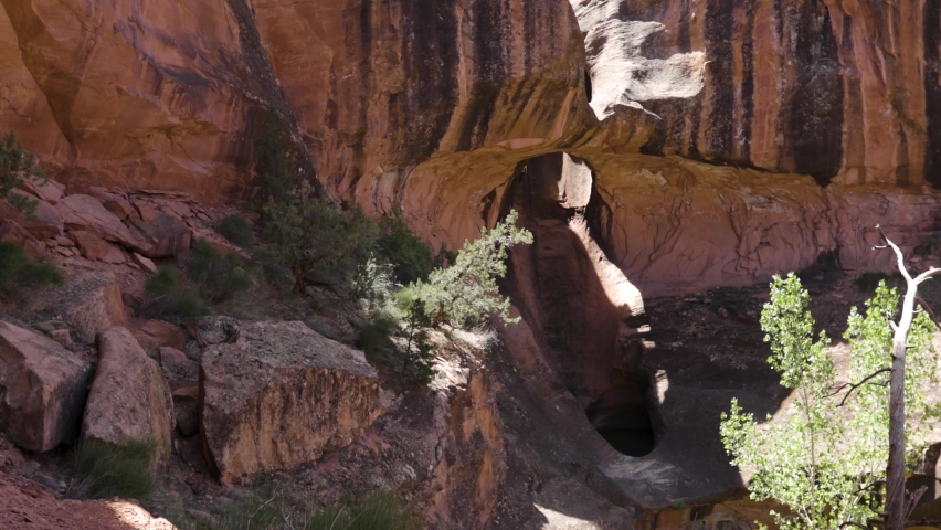 Man rappels through a sandstone arch in the American Southwest.