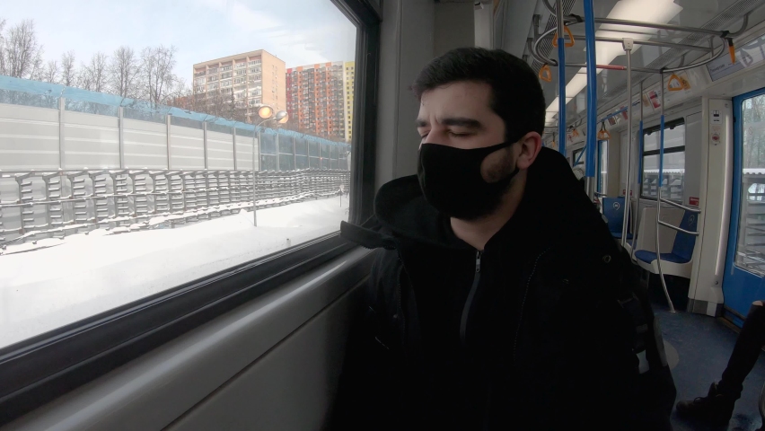 Moscow, Russia, 02.16.2021: a young European brunette in a mask rides a Moscow metro train. the guy looks out the window. winter cold day | Shutterstock HD Video #1067551724