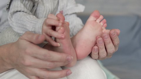 Cute curious pretty little baby playing with legs, counting toes, tickling feet