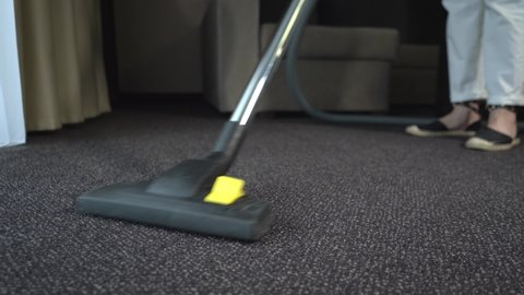 Hotel housekeeper vacuuming carpet covering in hotel suite