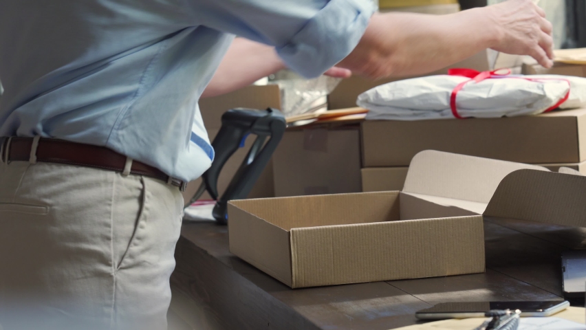 Close up view of older mature female online store small business owner worker packing package post shipping ecommerce retail order in box preparing delivery parcel on table. Dropshipping service.  Royalty-Free Stock Footage #1067562767