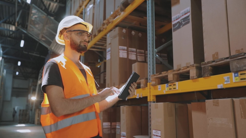 The worker inspects the goods in the warehouse. Warehouse manager enters data via tablet | Shutterstock HD Video #1067568323