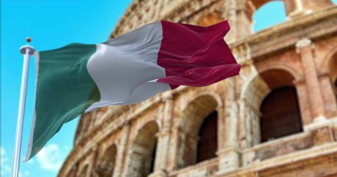 The Italian flag flapping in the wind with the Colosseum blurred in the background. Travel and tourism. Tourist attraction in Italy. Ancient Roman Empire and History. Flavian Amphitheater