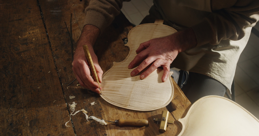 Cinematic shot of master artisan luthier working on creation of handmade fine quality wood violin in his creative workshop. Concept of spiritual instrument, handmade, art, orchestra, artisan, music. Royalty-Free Stock Footage #1067572169