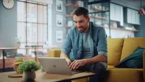 Smiling Caucasian Man Working on Laptop Computer while Sitting on a Sofa Couch in Stylish Cozy Living Room. Happy guy Having Fun at Home. Browsing Internet, Drinking Coffee from a Mug. - Powered by Shutterstock - Get 15% off with code: PIKWIZARD15