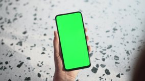 Close up of a woman's hand holding a mobile telephone with a vertical green screen in restaurant chroma key smartphone technology cell phone street touch message display hand