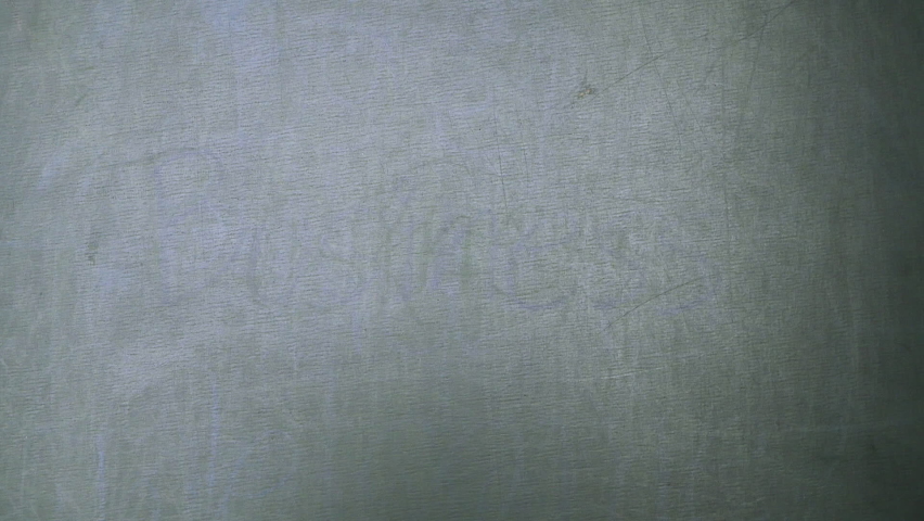 Close up of a woman holding a chalk and writing "Solar cell" on the blackboard.