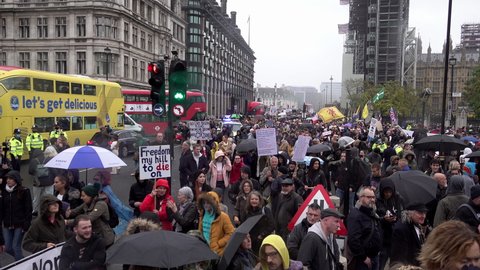 London , United Kingdom (UK) - 10 24 2020: Thousands of people march past a yellow bus on a Coronavirus and QAnon conspiracy protest 
