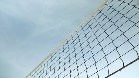 Looking up beach volleyball net, clear sky background, rainbow coloured ball flying above