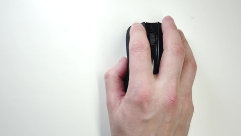 Close-up of male hand clicking mouse. Black computer mouse on a work desk. Working with a PC and clicking on the mouse.