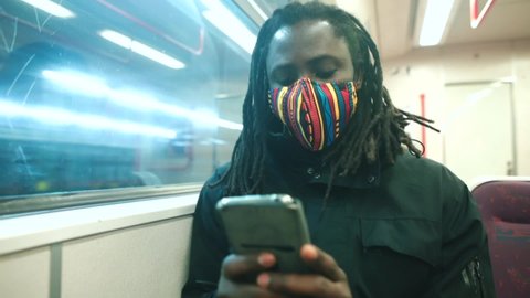 Back guy uses phone in hands while sitting in subway car station moving behind acne. Transportation passengers along route in city using public transport. 