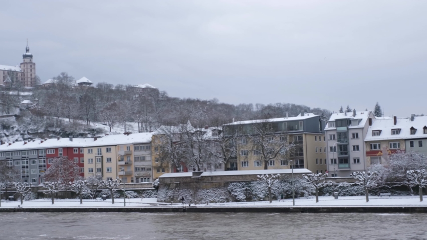 A man enjoy the view of the River Main, Festung Marienberg and the Alte Mainbrücke on a cold winter day in Würzburg. This beautiful historical german city is rarely coverd in snow. 4K, right to left