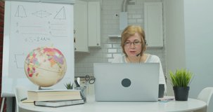 Adult woman in headphones talking to students via video conference at home. The teacher leads an online lesson for schoolchildren or students. Distance Learning, e-education, e-Learning, homeschooling