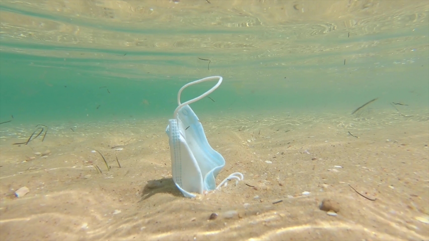 Used disposable surgical mask is moved by the waves on the seabed of the beach. Coronavirus is contributing to pollution Seas and Oceans