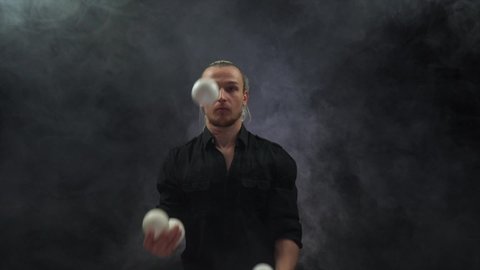 Man wearing a black juggling with white balls. Management, control and success