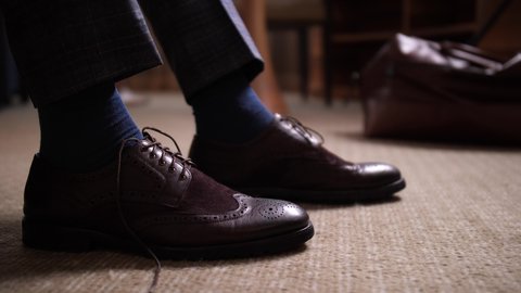 Close-up of male hands tying shoes, businessman going to meeting with business partners from hotel room. Dressing for business meeting, respectable appearance, formal clothing, dress code
