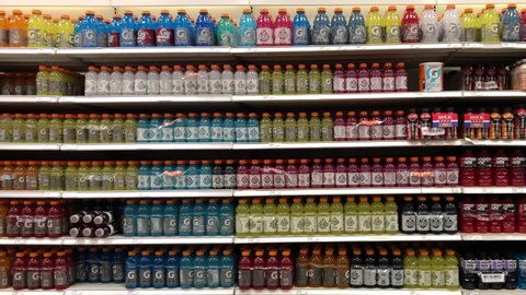 Oakland, CA - Feb 17, 2021: 4K HD video panning slightly across shelves stocked full of Gatorade and Powerade sports drinks in a colorful display.
