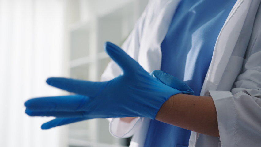 Young Asia lady doctor or nurse worker surgeon preparing for the surgical operation and wearing hand gloves at health clinic or hospital office. Social distancing, quarantine for coronavirus. | Shutterstock HD Video #1067618234