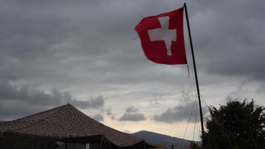 Aid station, field hospital. Surgical care to the wounded in the war. Red cross flag in the wind on mobile medical camp
