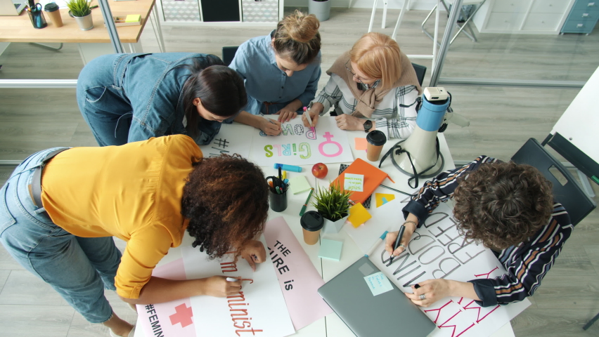 Group of active women feminists making posters for gender equality social movement talking enjoying creative work. Lifestyle and feminism concept. Royalty-Free Stock Footage #1067624015
