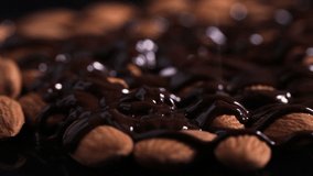 Almond nuts drizzled with melted chocolate and sprinkled with various seeds and nuts on a black background. Foodstuff, Healthy food, Diet. - Powered by Shutterstock - Get 15% off with code: PIKWIZARD15