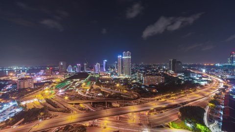 Aerial time lapse of Johor Bahru city with tall buildings in clear sky at night and busy traffic on elevated highway leading to CIQ. Prores Full HD