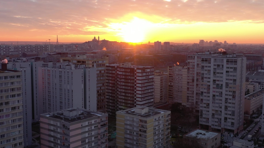 France, Paris suburb (Seine-Saint-Denis district), Aubervilliers, HLM buildings during sunset (or sunrise). Eiffel tower and Sacré-Coeur Basilica in back, drone aerial view flying through buildings | Shutterstock HD Video #1067637875