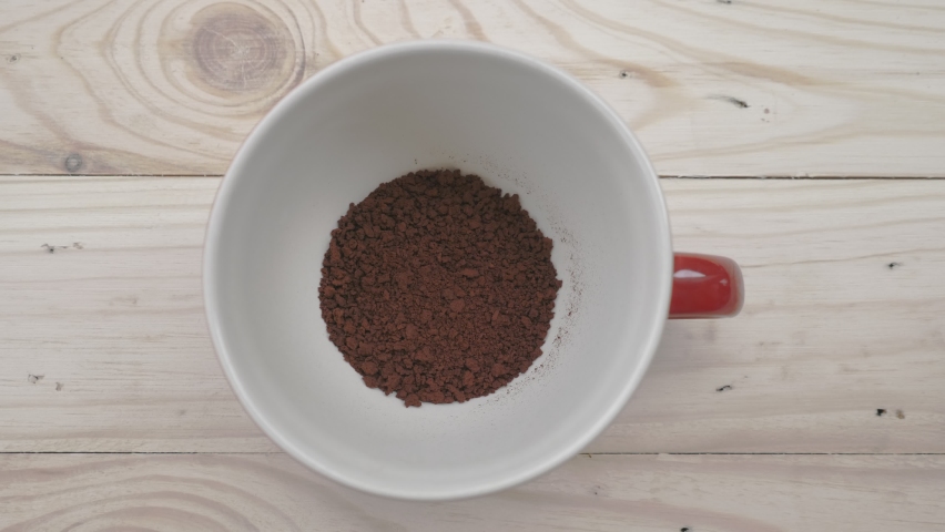 Up close at the top view, hot water is poured from the boiler into a red coffee cup with instant coffee inside. Royalty-Free Stock Footage #1067638460