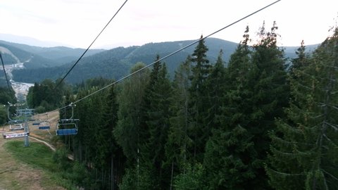 Scenic landscape in the mountains. Riding down the hill in a cable car. Blue ski lift or elevator used as a viewpoint during summer in Europe. Beautiful forest with trees outdoors and mountain range.