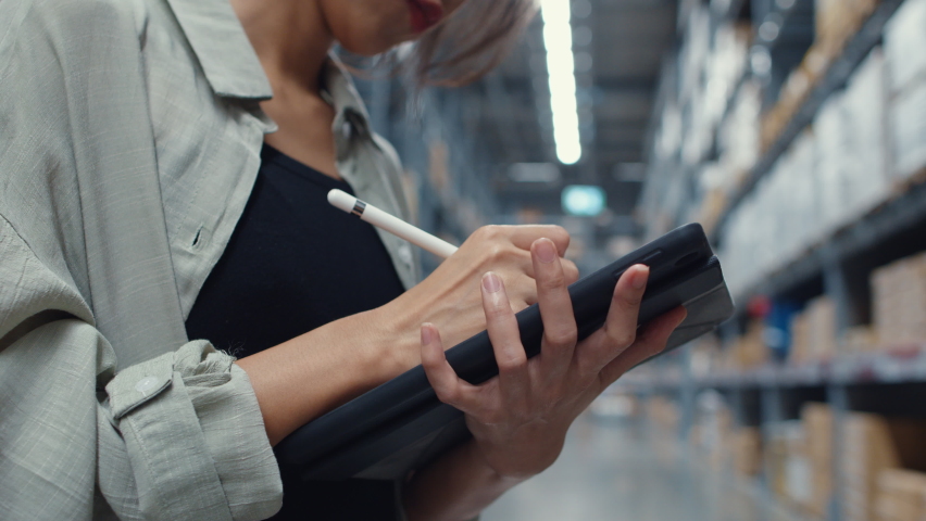 Attractive young Asia businesswoman manager looking for goods using digital tablet checking inventory levels standing in retail shopping center. Distribution, Logistics, Packages ready for shipment. Royalty-Free Stock Footage #1067652986