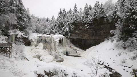 Slow motion wide angle view of Blackwater Falls in state park in Davis, West Virginia showing trail and observation deck in the winter with snow and ice.