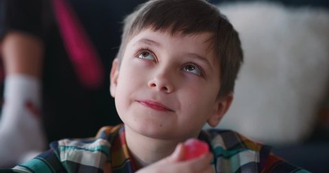 Close-up portrait of cute child boy eating a tasty candie closing eyes in satifaction enjoying leisure activity. Sugar addiction concept.