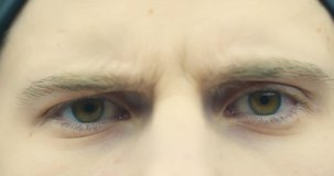 Brown eyes of male frowning looking at camera close up. 4K Video of handsome confident guy face