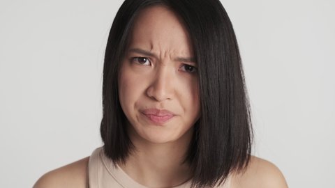 Close up angry Asian girl looking from eyebrows offended on boyfriend isolated over white background. Irate face expression