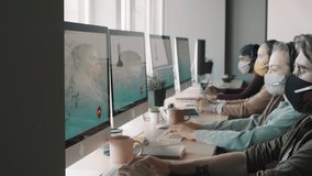 PAN shot of call center operators wearing face masks and headsets working on computers and answering calls in office - Powered by Shutterstock - Get 15% off with code: PIKWIZARD15