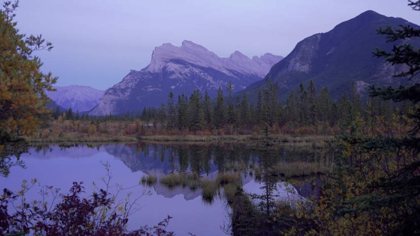 Vermilion Lakes autumn foliage scenery in dusk. Banff National Park, Canadian Rockies, Alberta, Canada. Colorful trees in red, yellow, golden colors. Mount Rundle, Sulphur Mountain in background.